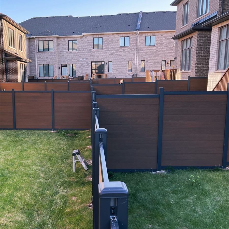 Brown horizontal privacy fence meeting a black metal railing