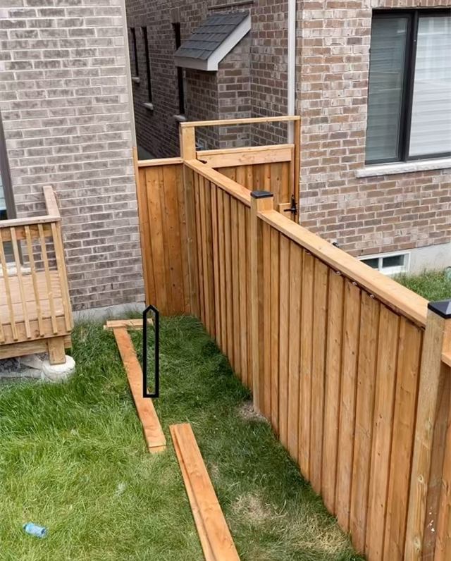Cedar board fence along the side of a brick house
