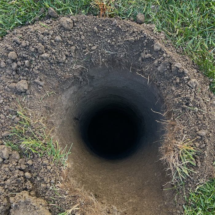 Freshly dug post hole in a lawn