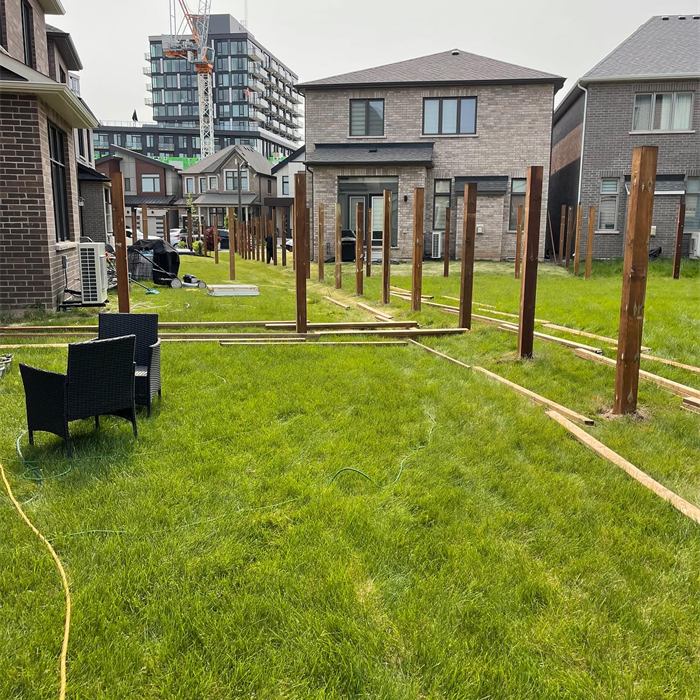 Row of new wood posts standing in a straight line behind townhomes